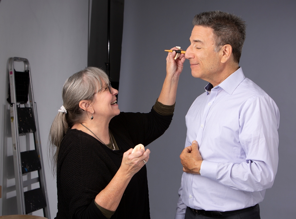 Makeup artist touching up Mark Miller for his headshot session